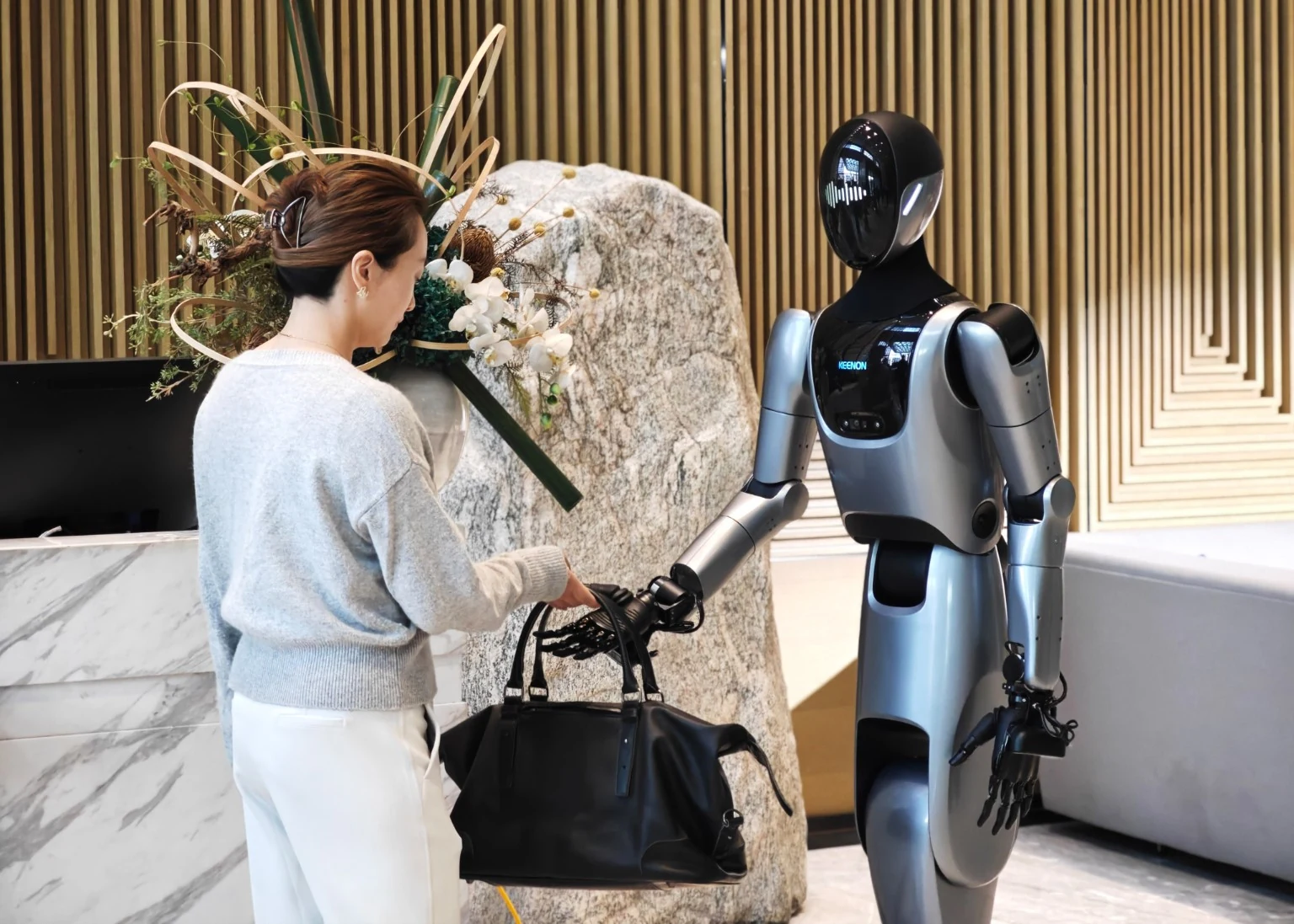 Robot humanoide KEENON recibiendo a una huésped en la recepción de un hotel